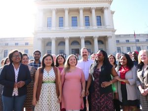 Grup divers de oameni uniți în fața unei clădiri guvernamentale.